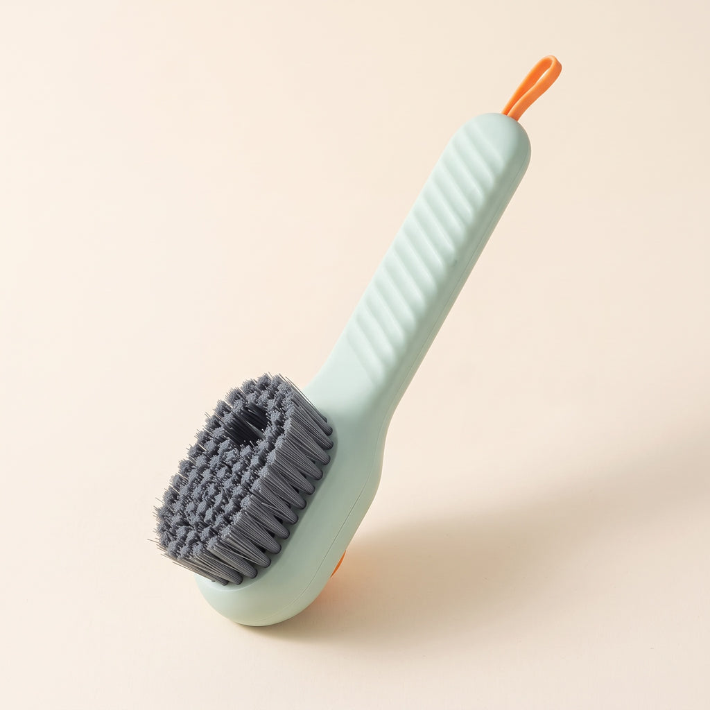 Brosse KleanKicks vert sauge à réservoir avec poils gris, manche strié et boucle orange