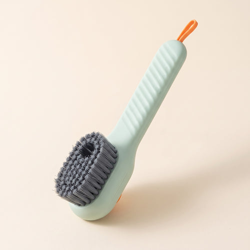 Brosse KleanKicks vert sauge à réservoir avec poils gris, manche strié et boucle orange